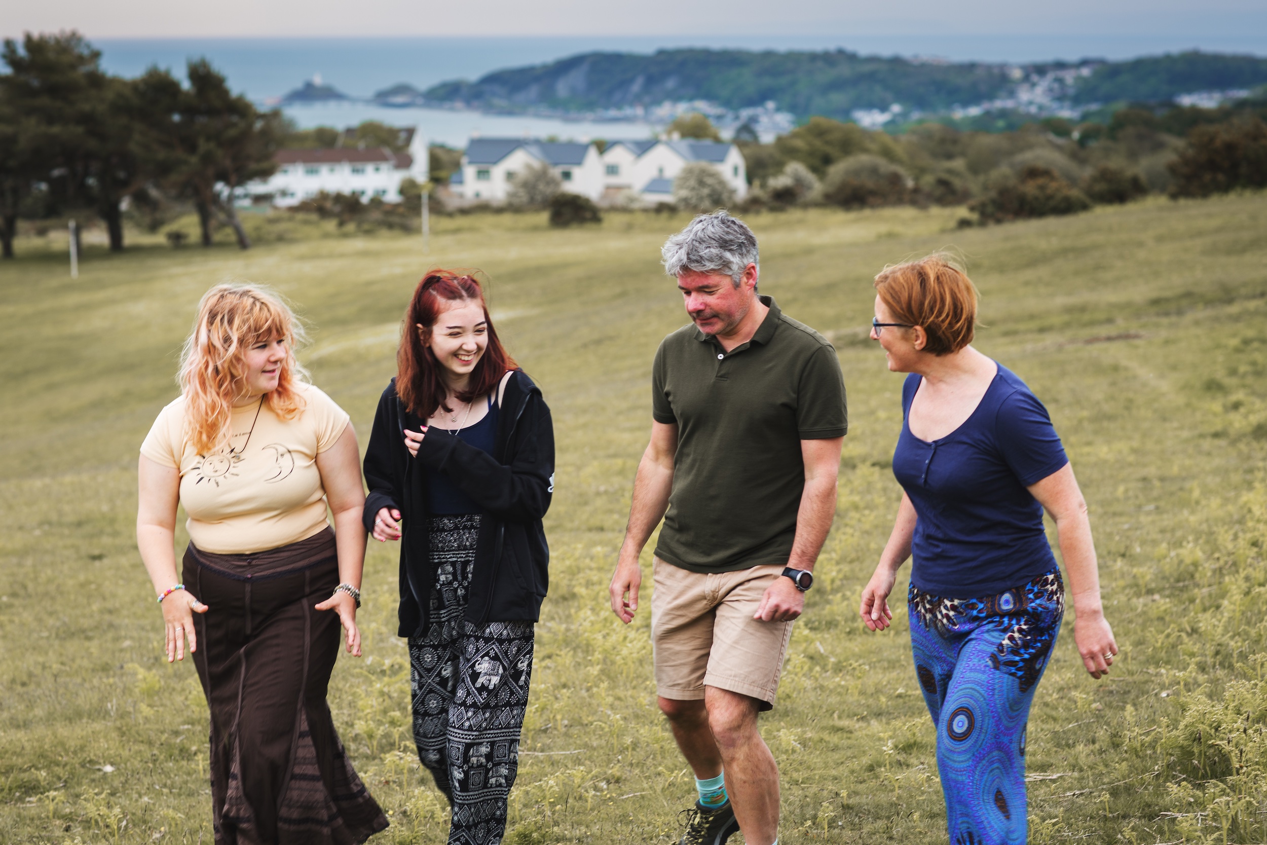 Two adults and two teenagers walking in field in Swansea
